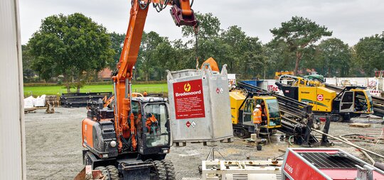 Der Hitachi Mobilbagger hantiert mit Kraftstofftanks präzise über das Baustellenfeld.